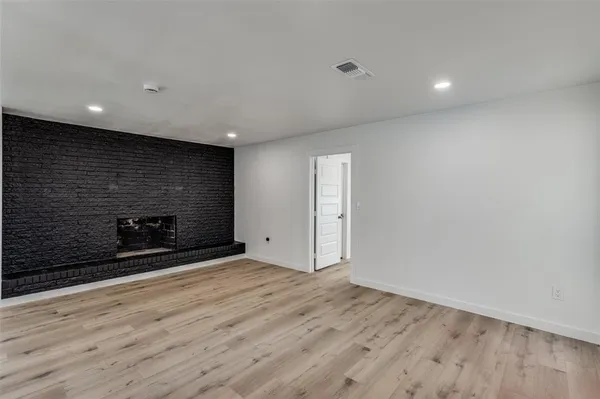 a view of an empty room with wooden floor and a fireplace