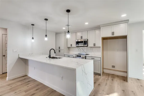 a kitchen with stainless steel appliances kitchen island a sink a stove a refrigerator and cabinets