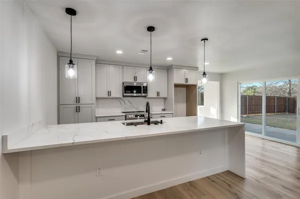 a view of a kitchen with kitchen island a sink stainless steel appliances and cabinets