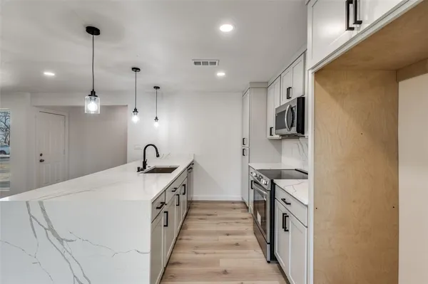 a kitchen with stainless steel appliances granite countertop a sink a stove and a refrigerator