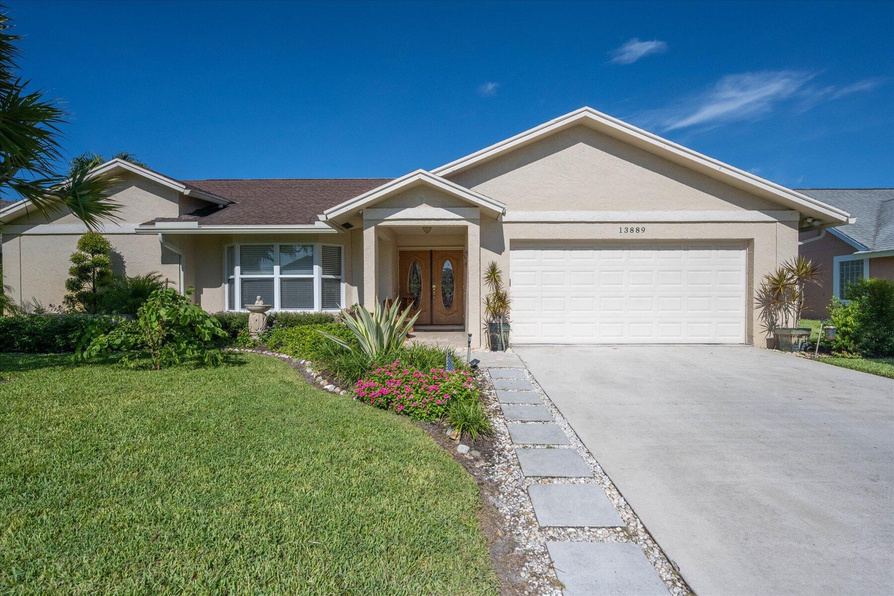 13889 Geranium Place Wellington, FL 33414 - Photo 1 of 32 a front view of a house with a yard and garage