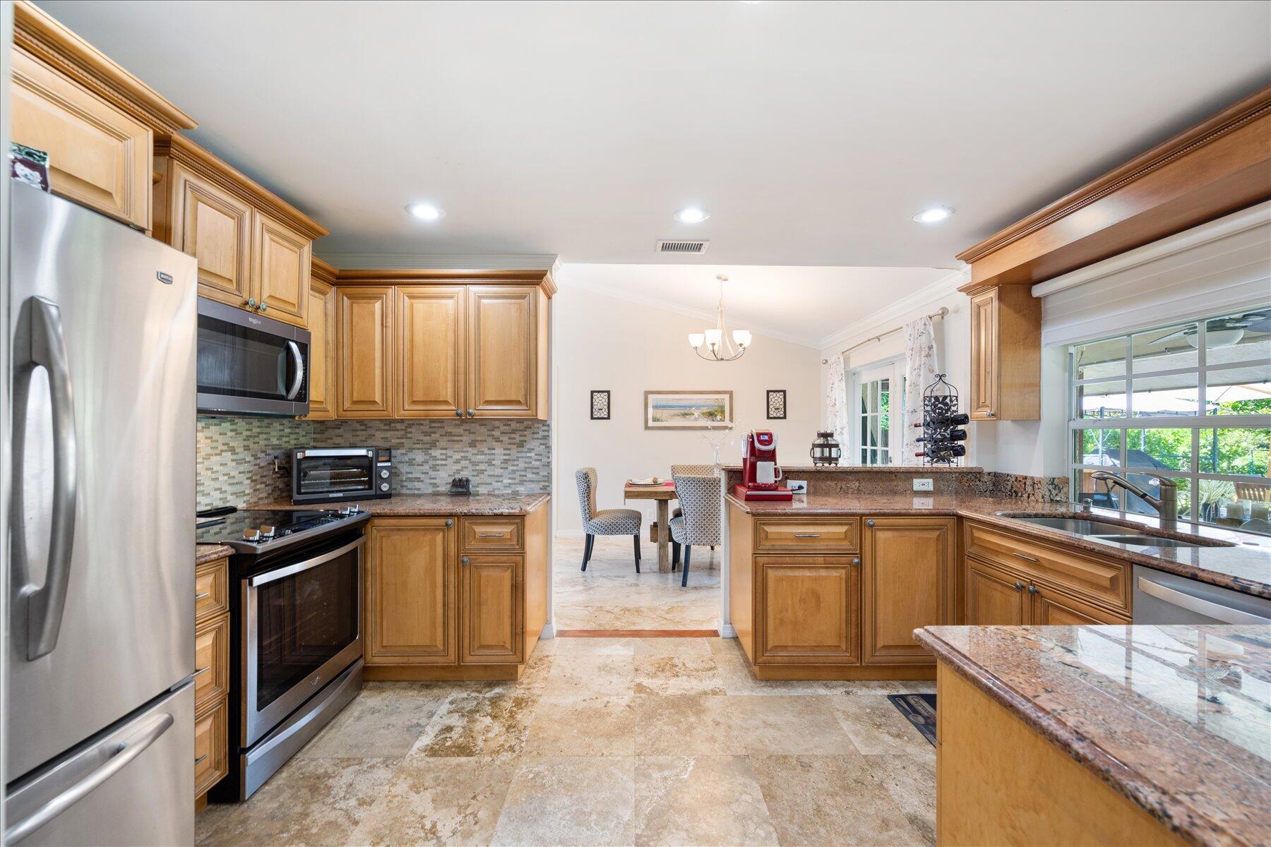 13889 Geranium Place Wellington, FL 33414 - Photo 10 of 32 a kitchen with stainless steel appliances granite countertop a sink stove and refrigerator