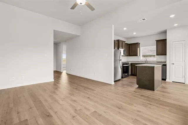 a view of kitchen with stainless steel appliances granite countertop a stove top oven a sink dishwasher a refrigerator and a dining table with wooden floor