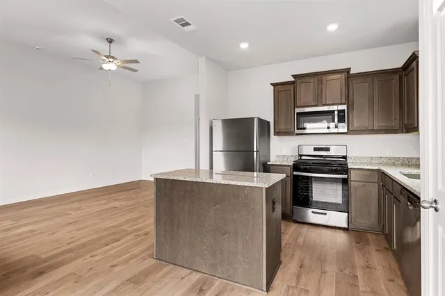 a kitchen with kitchen island a counter top space stainless steel appliances and cabinets