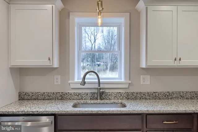 a kitchen with granite countertop a sink and white cabinets