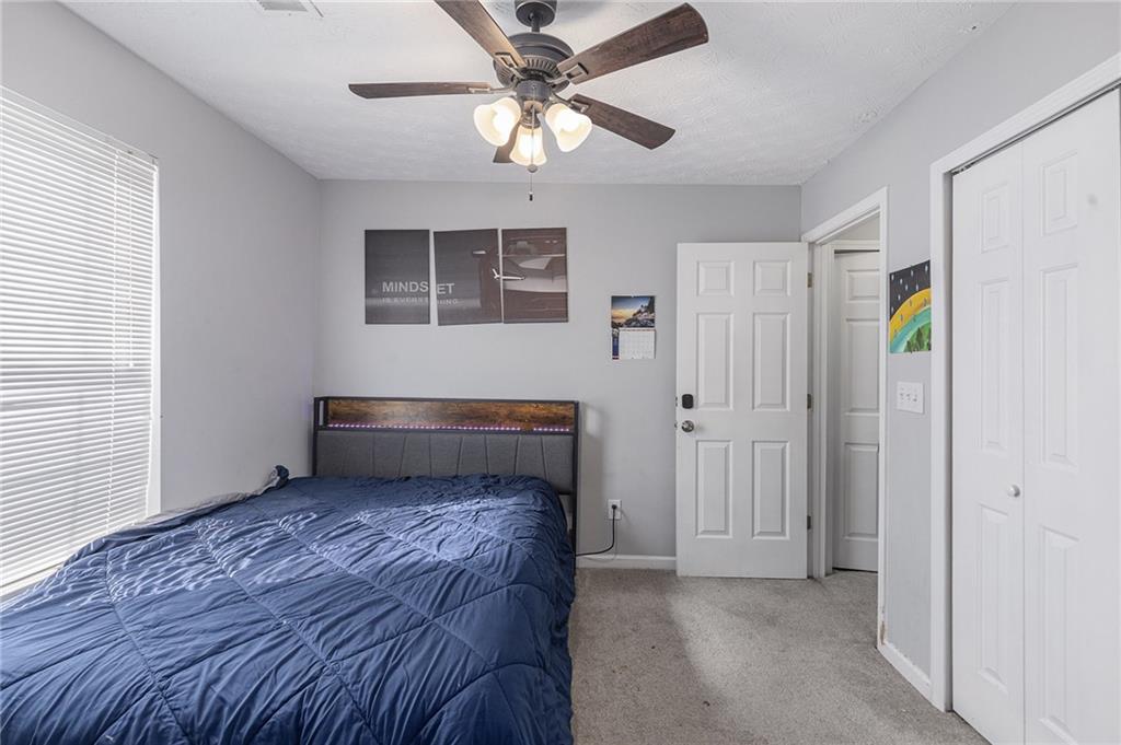 6536 Arbor Gate Drive Southwest, Unit 2 Mableton, GA 30126 - Photo 16 of 27 a bedroom with a bed and a ceiling fan