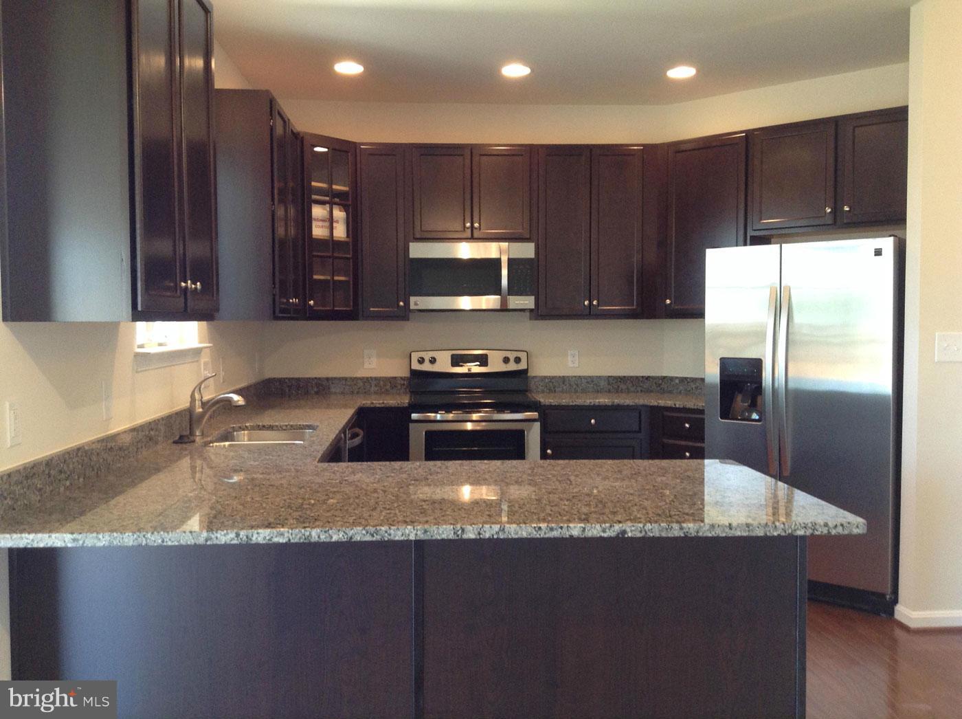 5279 Longbow Road King George, VA 22485 - Photo 2 of 30 a kitchen with kitchen island granite countertop wooden cabinets a refrigerator and a sink