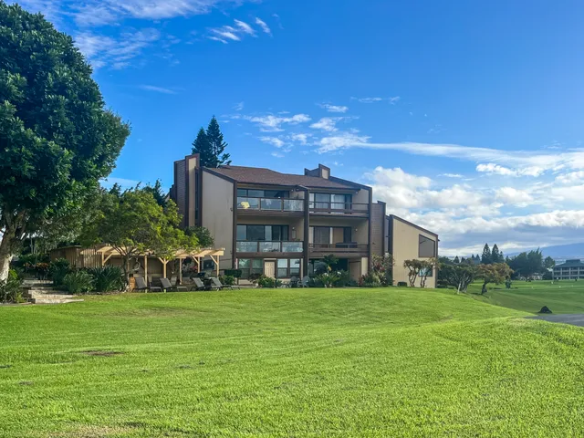 a view of a house with a big yard and large trees