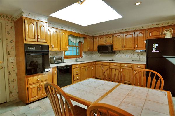 12 Quadrant Road Salem, MA 01970 - Photo 3 of 9 a kitchen with stainless steel appliances kitchen island granite countertop a refrigerator a stove top oven and a sink with wooden cabinets