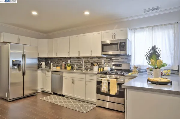 a kitchen with white cabinets sink and stove