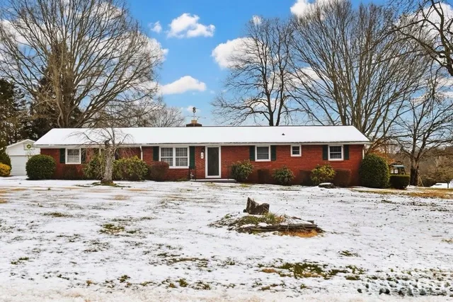 a front view of a house with a yard covered in snow
