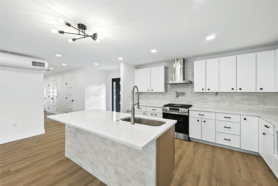 815 Buckingham Place Austin, TX 78745 - Photo 11 of 33 a kitchen with stainless steel appliances kitchen island granite countertop a stove a sink a refrigerator and white cabinets with wooden floor