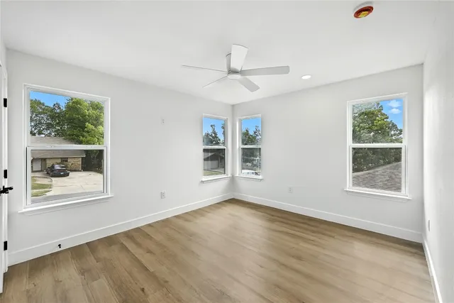 a view of an empty room with a window and wooden floor