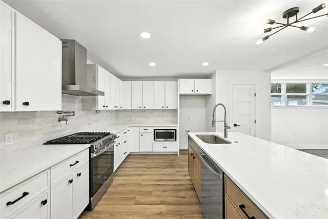 a kitchen with granite countertop a sink stainless steel appliances and white cabinets