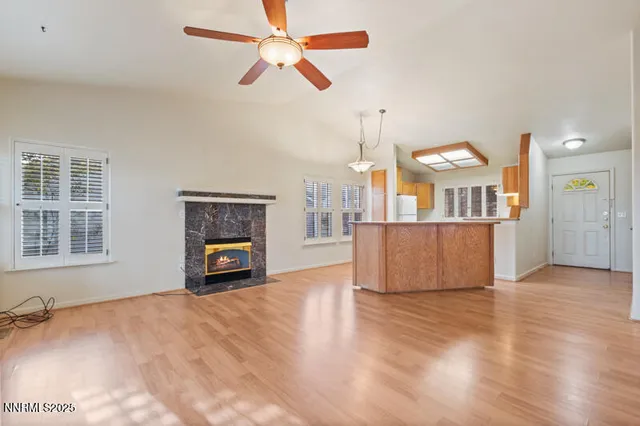 a view of a livingroom with a fireplace a ceiling fan and wooden floor