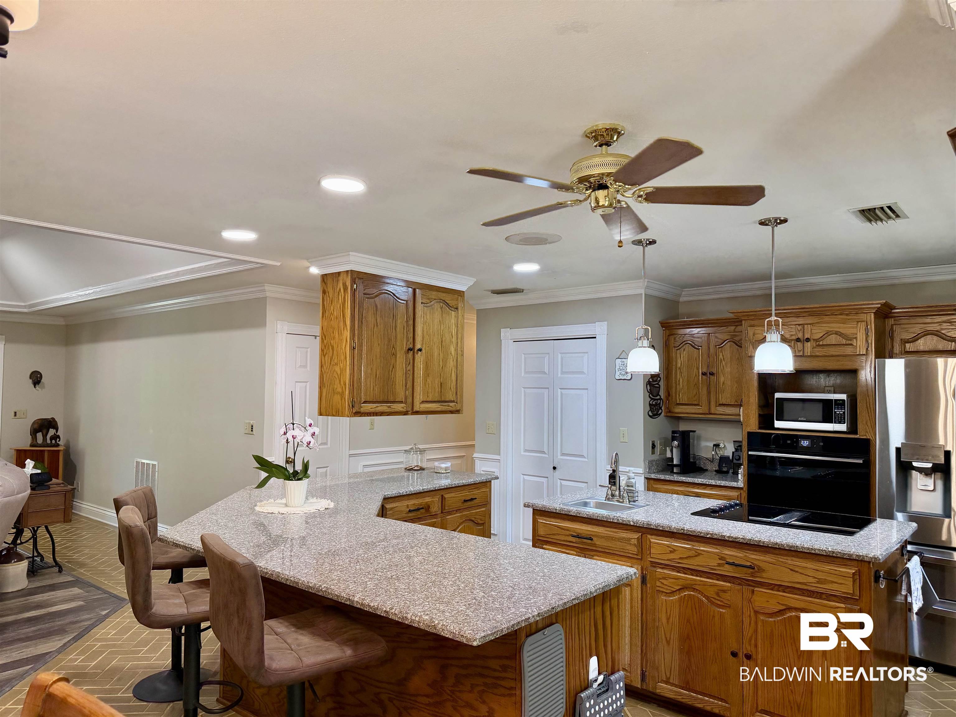 2944 Appleton Road Brewton, AL 36426 - Photo 5 of 65 Kitchen featuring a peninsula, wood finish cabinets, a kitchen island with sink, black appliances, and a kitchen breakfast bar