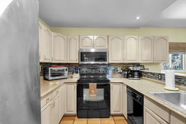 a kitchen with stainless steel appliances granite countertop a stove top oven a sink a counter space and cabinets
