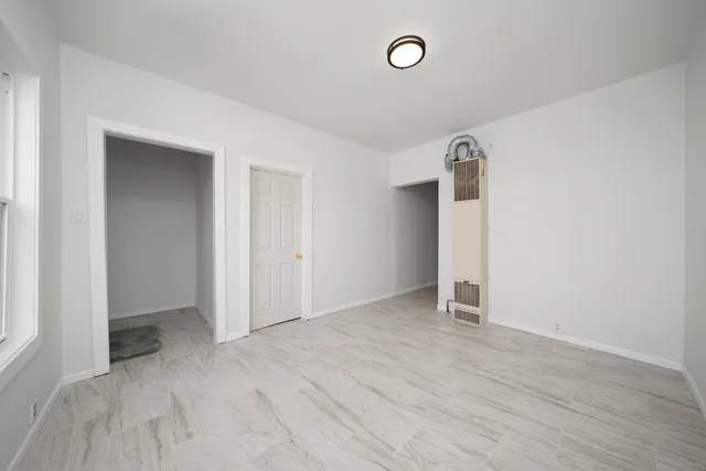 an empty room with closet and windows