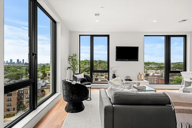 a living room with furniture tv and large windows