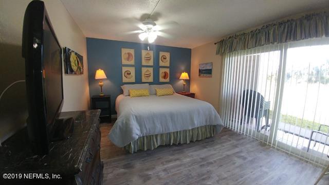 4 Ocean Trace Road, Unit 108 St. Augustine, FL 32080 - Photo 7 of 21 a spacious bedroom with a bed and a chandelier