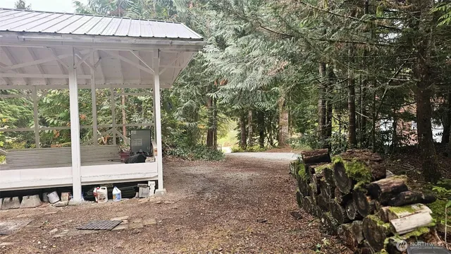 a view of a patio with a table and chairs under an umbrella with large trees