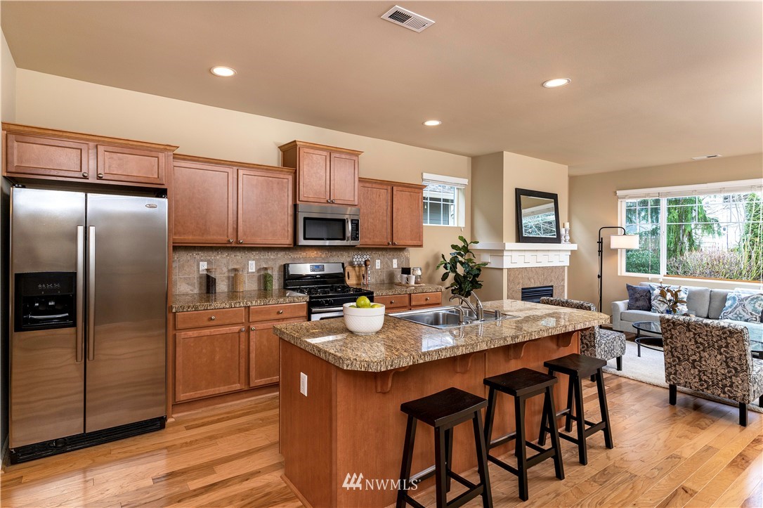 3801 219th Place Southeast Bothell, WA 98021 - Photo 4 of 22 a kitchen with granite countertop a table chairs microwave and refrigerator