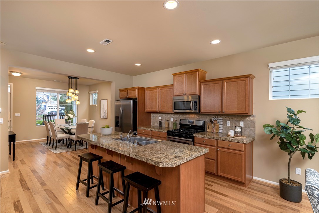 3801 219th Place Southeast Bothell, WA 98021 - Photo 7 of 22 a kitchen with granite countertop a table chairs stove and cabinets