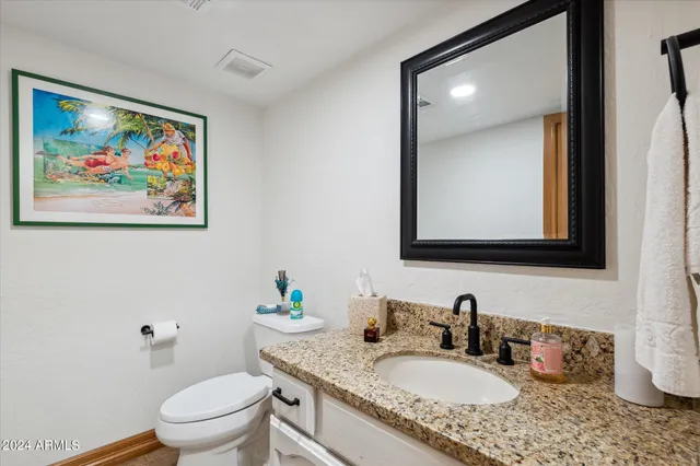a bathroom with a granite countertop toilet a sink and mirror