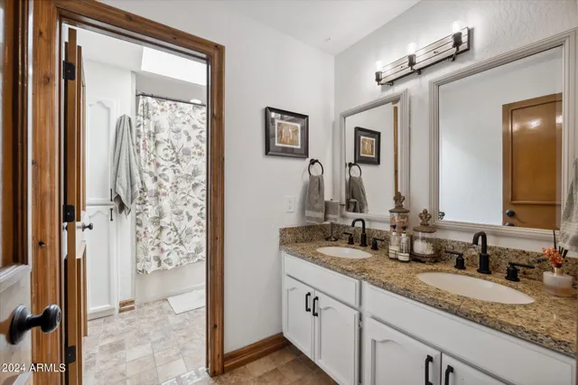 a bathroom with double vanity sinks and a shower