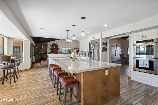 a dining hall with stainless steel appliances kitchen island a table and chairs