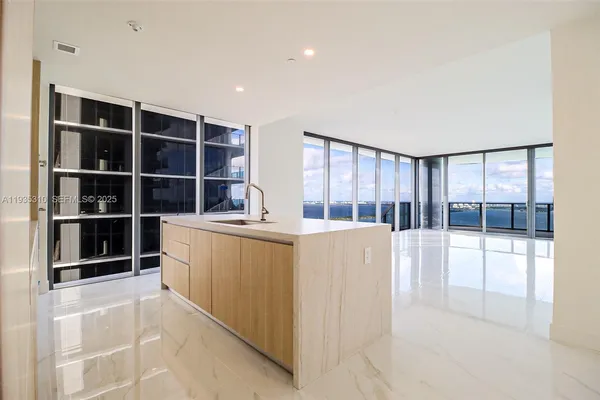 a large kitchen with kitchen island a large counter top and stainless steel appliances