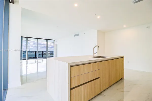 a view of an empty room and a kitchen