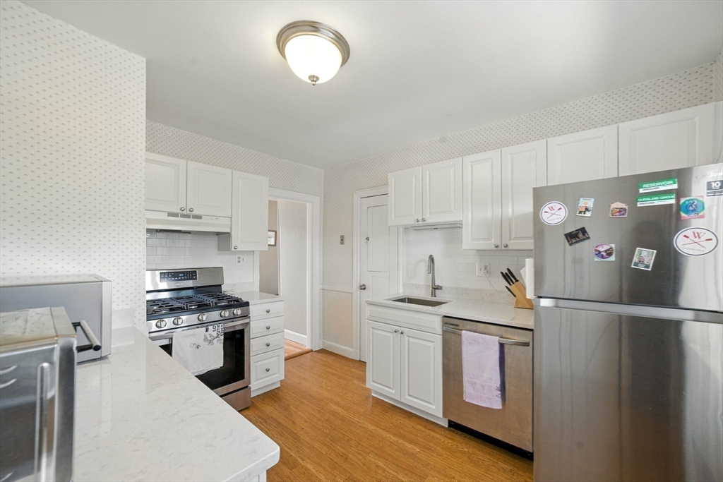 84 Strathmore Road, Unit 7 Boston, MA 02135 - Photo 7 of 17 a kitchen with granite countertop a sink cabinets and stainless steel appliances