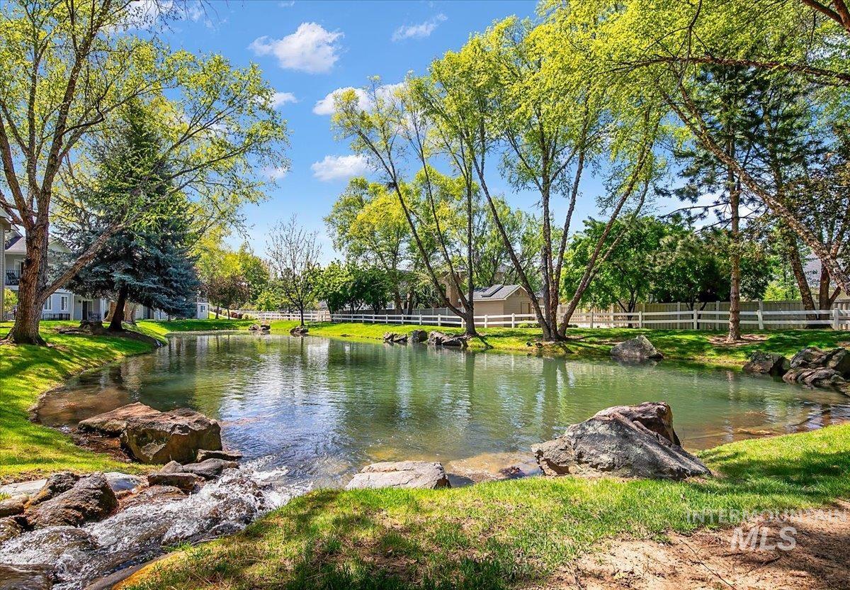 725 North Eagle Road Eagle, ID 83616 - Photo 37 of 45 Serene pond with a natural stream feature, surrounded by lush green grass and mature trees