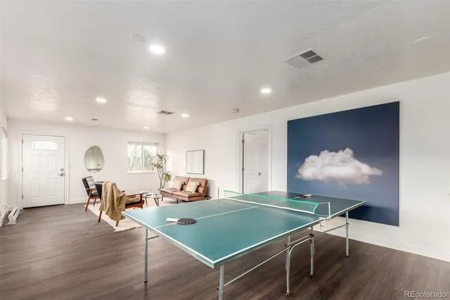 a room with wooden floor pool table and chairs
