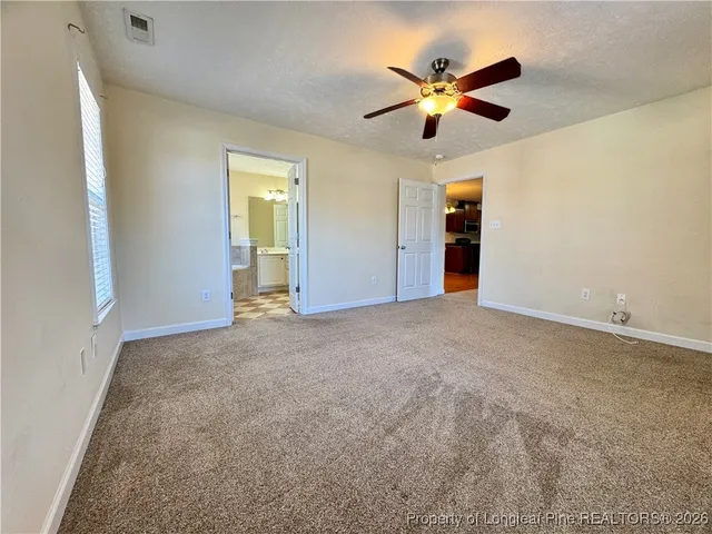 a view of an empty room with cabinet and a ceiling fan