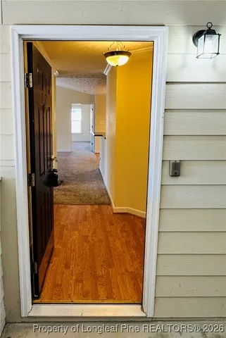 a view of a hallway with wooden floor and a living room