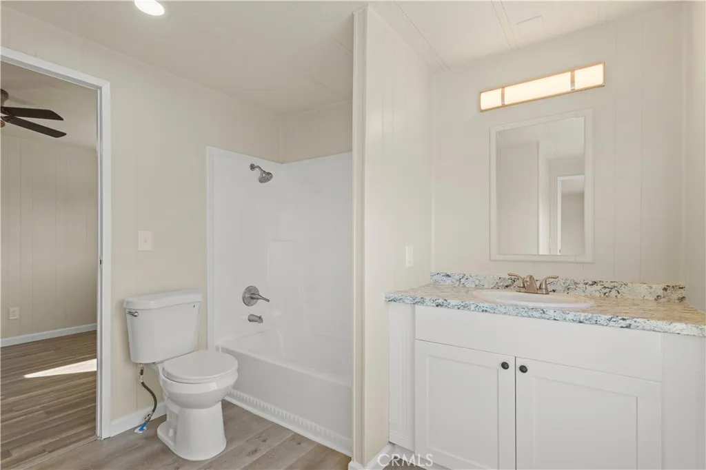 1097 North N State, Unit 194 Hemet, CA 92543 - Photo 13 of 19 a bathroom with a granite countertop toilet a sink and a mirror