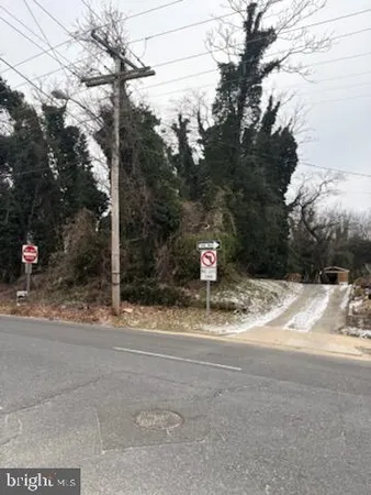 a view of a road with a tiny house and a sign board