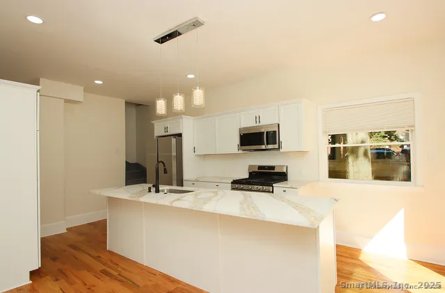 a kitchen with stainless steel appliances a sink a microwave a refrigerator and white cabinets
