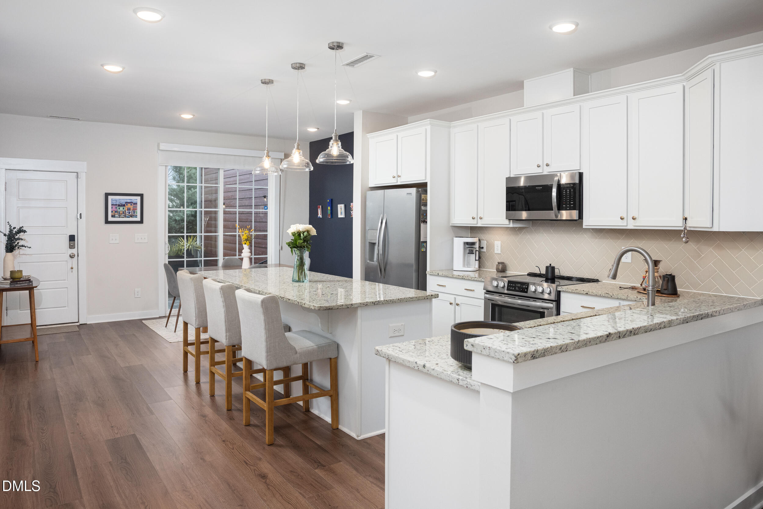 469 Rally Point Place Wake Forest, NC 27587 - Photo 3 of 37 a kitchen with stainless steel appliances granite countertop a stove top oven a sink a refrigerator white cabinets and a dining table with wooden floor