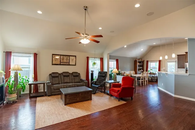 a living room with furniture kitchen view and a wooden floor