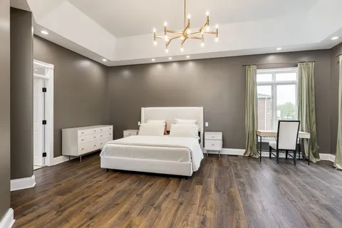 a spacious bedroom with a bed and wooden floor