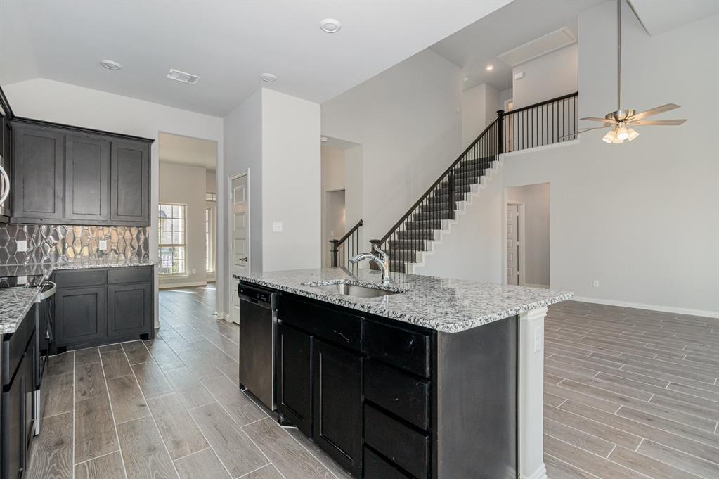 232 Cisco Trail Forney, TX 75126 - Photo 25 of 27 a kitchen with granite countertop a stove a refrigerator and a wooden cabinets