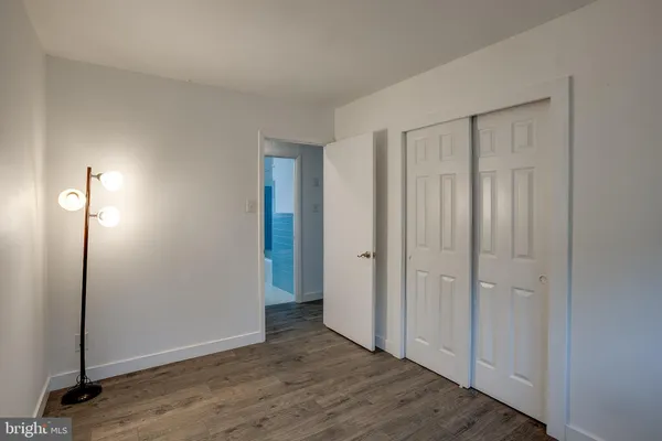 a view of an empty room with wooden floor and a bathroom