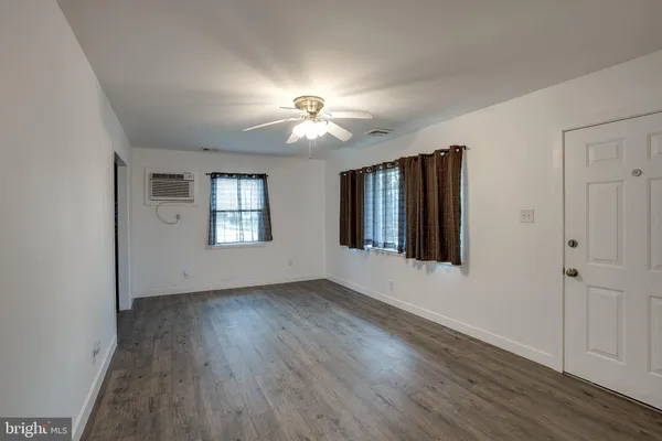 an empty room with wooden floor chandelier fan and windows