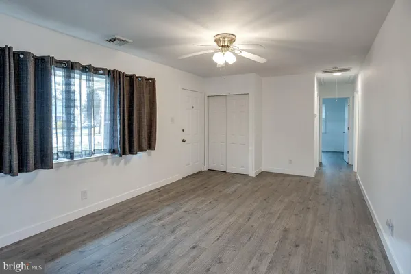 a view of an empty room with a window and wooden floor
