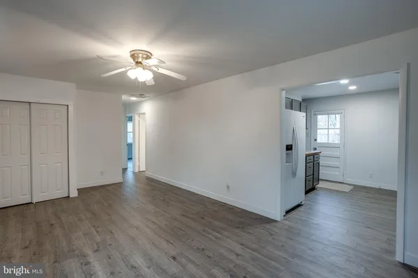 a view of an empty room with wooden floor and a ceiling fan