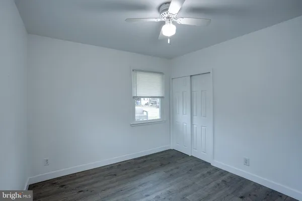 an empty room with wooden floor chandelier fan and windows