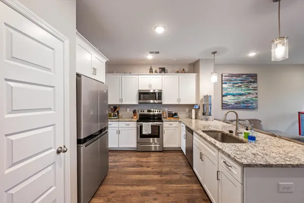a kitchen with stainless steel appliances granite countertop a refrigerator a sink dishwasher a stove and a refrigerator